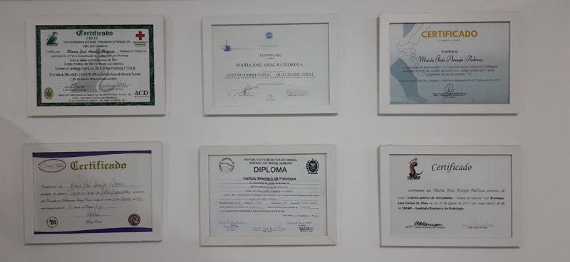 Certificados e diplomas emoldurados na parede da clínica